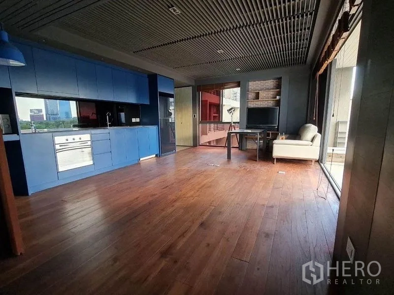 คอนโด ขายในPathum Wan, Bangkok - พื้นที่เปิดโล่งพร้อมครัวบิลท์อินสีฟ้าและหน้าต่างกว้าง