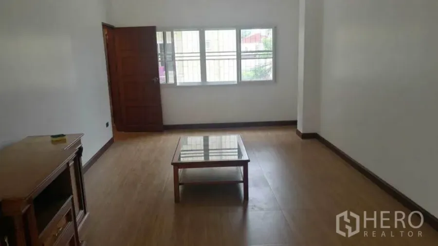Townhouse for rent in Khlong Toei, Bangkok - Simple lounge with wood flooring, window grills and a small coffee table.