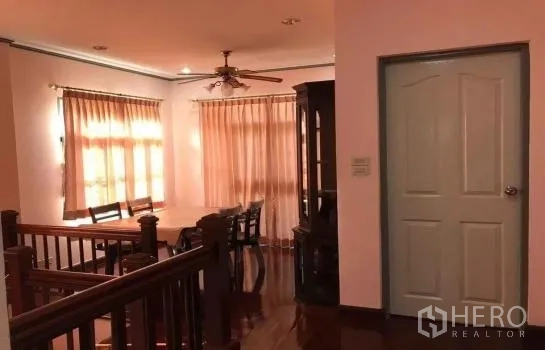 Detached House for rent in Khlong Sam Wa, Bangkok - Upstairs dining area with wood floors, ceiling fan and large windows dressed in sheer curtains.
