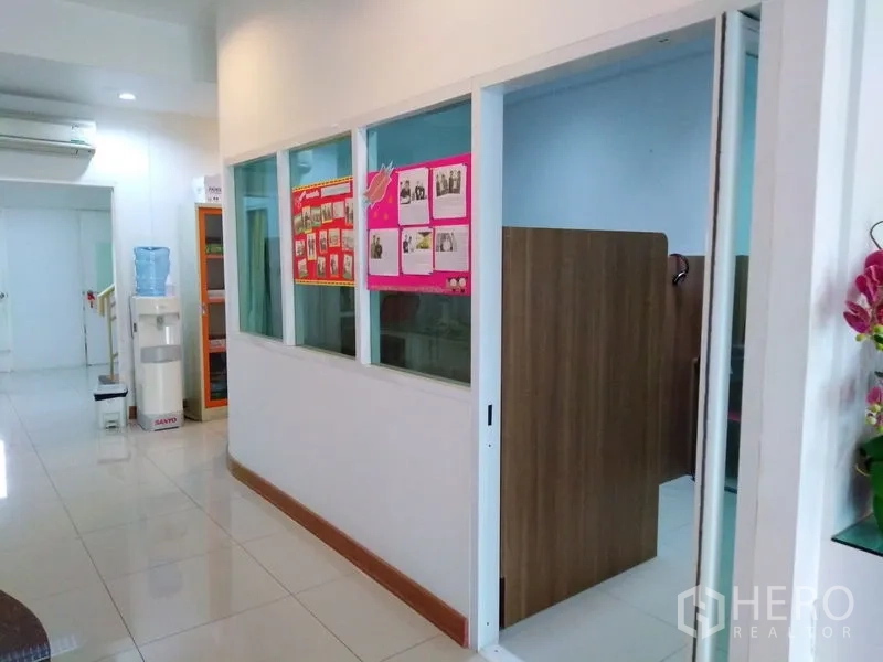Office Space for sale in Bang Kapi, Bangkok - Bright corridor with glass-partitioned office rooms, tiled floors and a water dispenser.