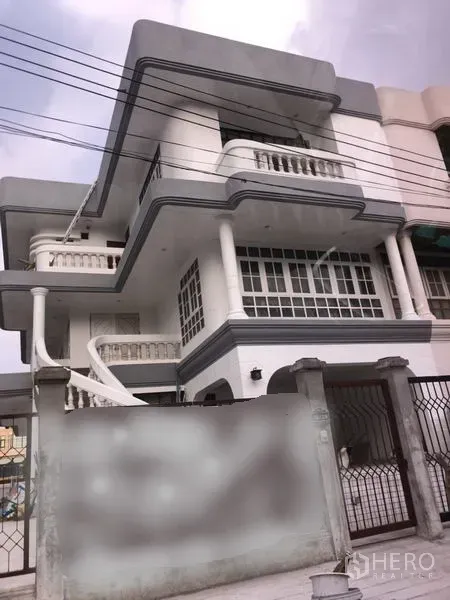 Home Office for rent in Wang Thonglang, Bangkok - Three-storey white home office in Wang Thonglang, Bangkok with balconies, columns, an exterior spiral staircase and a gated frontage.