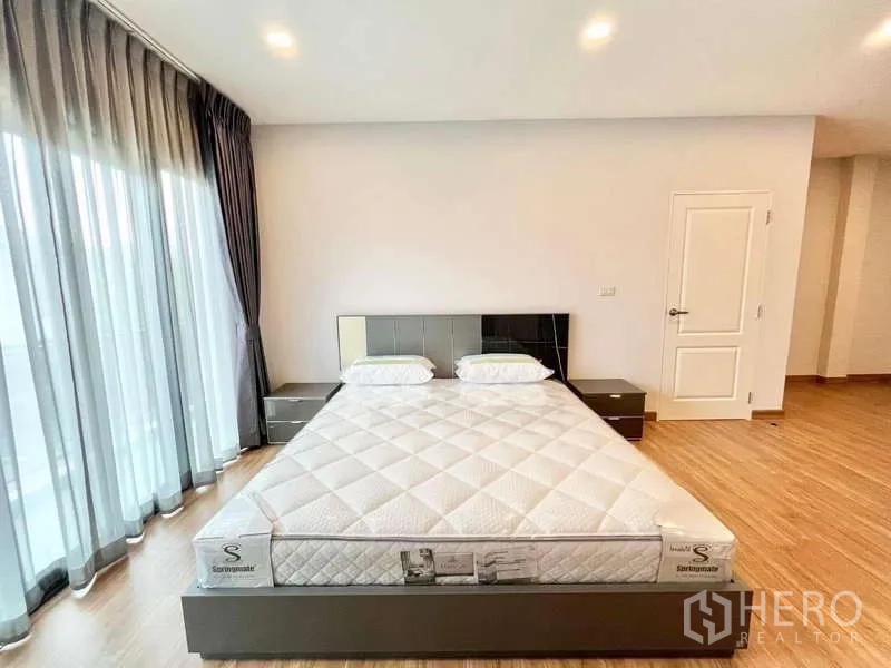 Detached House for rent in Don Mueang, Bangkok - Master bedroom with king bed, side tables and sliding doors to balcony.