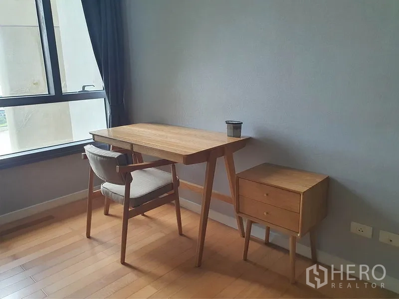 Condominium for rent in Yan Nawa, Bangkok - Compact work-from-home corner with wooden desk and chair by the window.