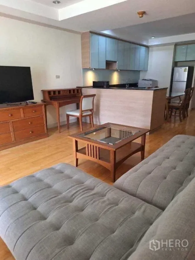 Apartment for rent in Watthana, Bangkok - Open living area with sectional sofa, glass-top coffee table and breakfast-bar kitchen.