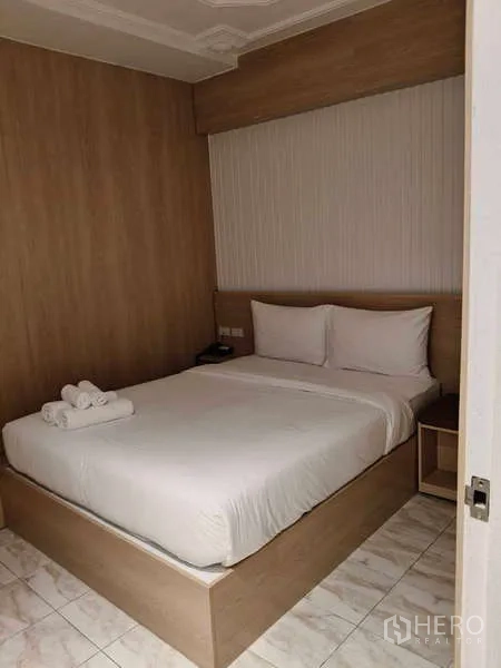 零售空间 出租在Khlong Toei, Bangkok - 温馨双人床房，木质装饰与床头搁架。