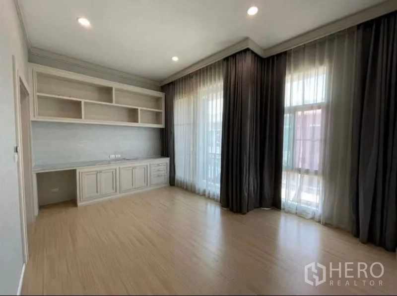 ทาวน์เฮาส์ ขาย - มุมห้องนอนรับแสงธรรมชาติ พร้อมชั้นวางของ โต๊ะทำงาน และหน้าต่างสูงพร้อมม่านสองชั้น