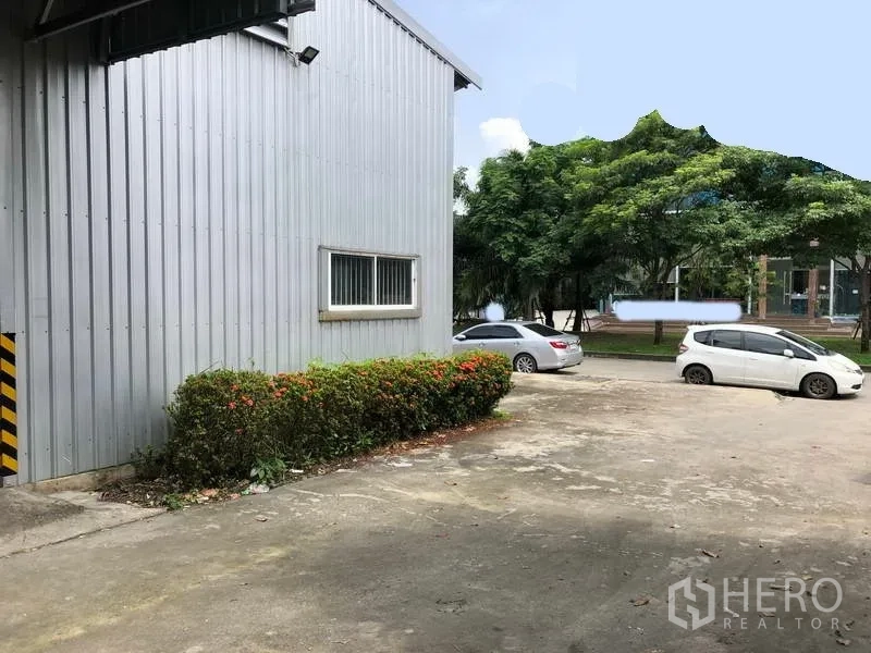 คลังสินค้า ให้เช่าในPak Kret, Nonthaburi - มุมด้านข้างโกดัง มีหน้าต่าง เตียงต้นไม้ และพื้นที่จอดรถกว้างติดถนนร่มรื่น