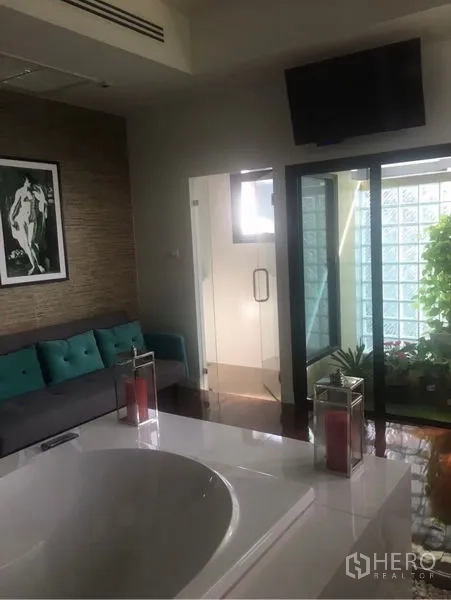Detached House for sale in Saphan Sung, Bangkok - Luxury bathroom lounge with soaking tub, sofa seating, glass block wall and garden view.