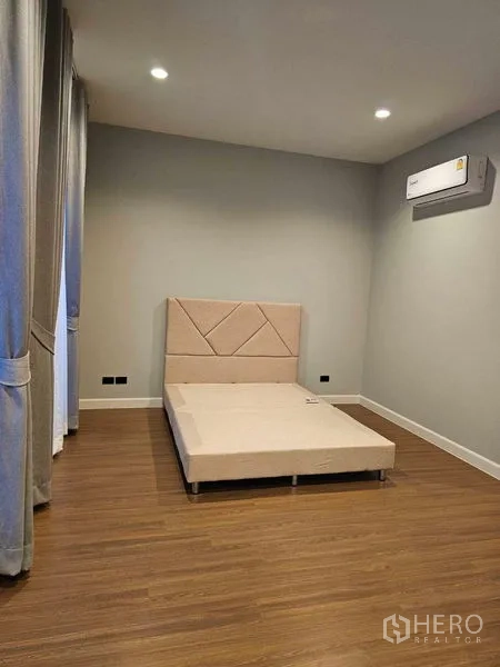 Detached House for rent in Mueang Pathum Thani, Pathum Thani - Bedroom with upholstered bedframe, wood floor and wall-mounted air-conditioner