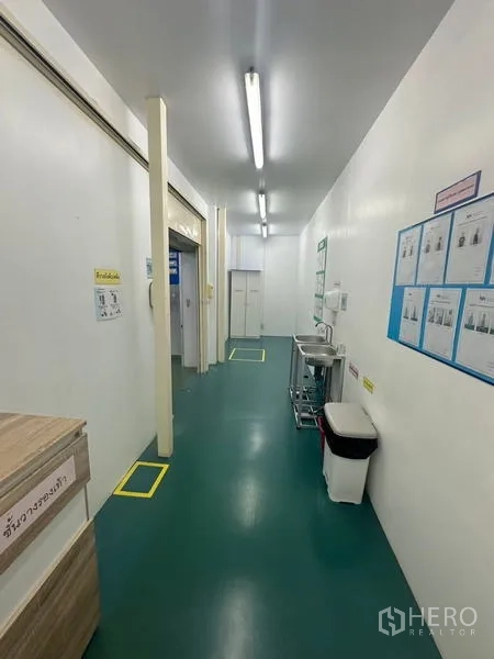 คลังสินค้า ให้เช่าหรือขายในLam Luk Ka, Pathum Thani - โถงทางเดินสะอาดสว่าง มีอ่างล้างมือ ป้ายความปลอดภัย และพื้นอีพ็อกซีสีเขียว