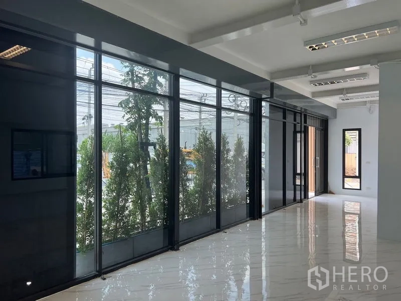 货栈 出租在Bang Sao Thong, Samut Prakan - 长廊式办公区，落地玻璃配百叶，可见外侧绿篱景观。