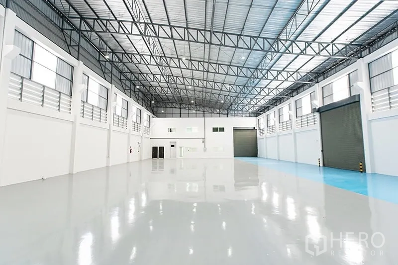 Warehouse for rent in Bang Bo, Samut Prakan - Spacious high-bay warehouse interior with glossy epoxy floor and multiple roller doors.