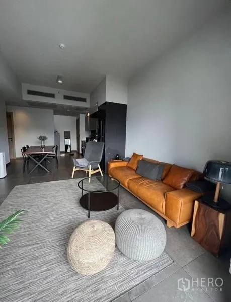 Condominium for rent in Watthana, Bangkok - Living and dining space with sofa, poufs and view toward the kitchen and entry.