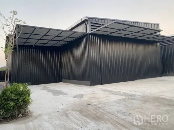 Warehouse for rent in Wang Thonglang, Bangkok - Front loading area with roof canopy, drainage grates and small landscaped shrubs.