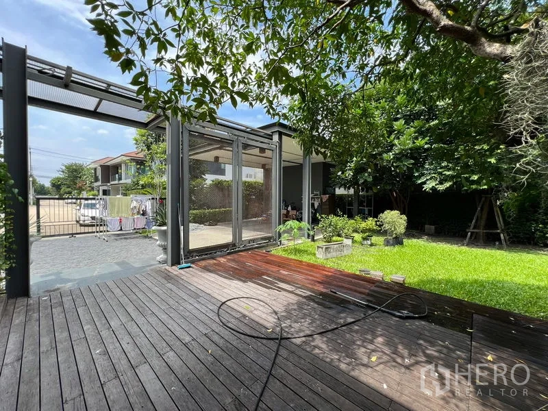 Detached House for sale in Bang Kapi, Bangkok - Shaded wooden terrace overlooking a private lawn and mature trees.