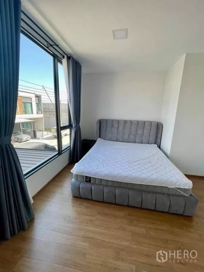 Townhouse for rent in Bang Phli, Samut Prakan - Master bedroom with panoramic corner windows and upholstered bed.