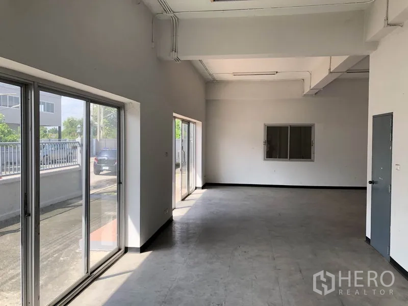 工厂 出租在Pathum Thani - 一层办公室/展示区，推拉玻璃门通向车道。