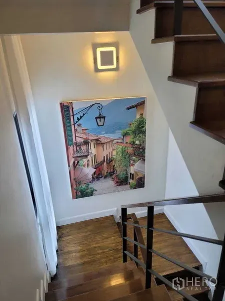 独立式住宅 出租或出售在Prawet, Bangkok - 木质楼梯，墙面灯与一幅大型风景画。