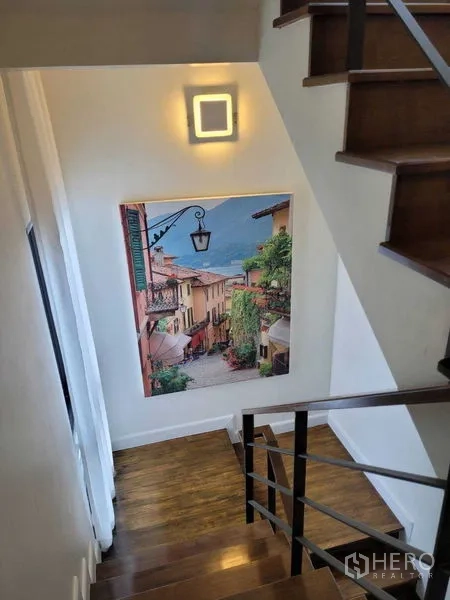 独立式住宅 出租或出售在Prawet, Bangkok - 木质楼梯，墙面灯与一幅大型风景画。