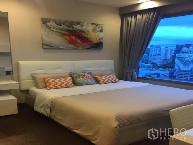 คอนโด ให้เช่าในRatchathewi, Bangkok - ห้องนอนโทนสบายตา เตียงบุหนังและงานศิลป์ ผนังหน้าต่างกว้างมองเห็นวิวเมืองยามเย็น