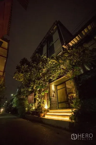 店屋 出租或出售在Din Daeng, Bangkok - 夜间外观，多层临街商铺楼，外墙暖色灯光、绿植和通往入口的台阶。