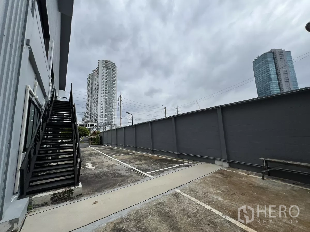 货栈 出租在Yan Nawa, Bangkok - 专属停车位与外部楼梯，背景为市区高楼。