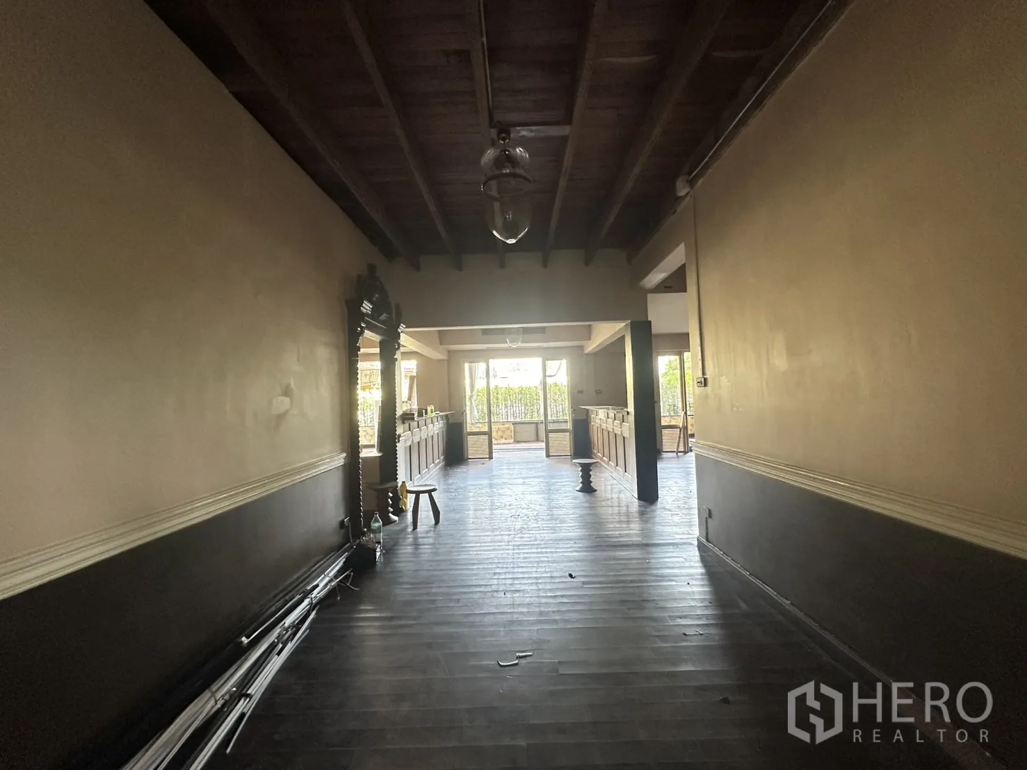 Detached House for rent - Long hallway with exposed beams leading toward bright doors and serving counter.