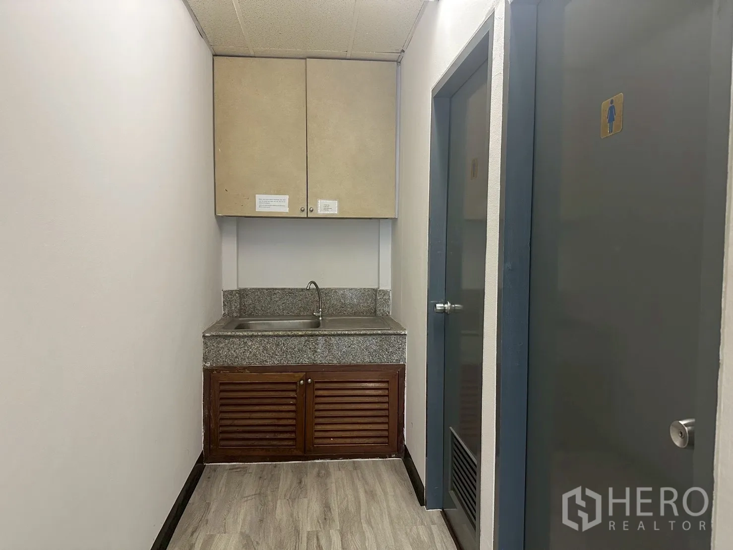 Office Space for rent - Compact pantry with sink and cabinets beside separate male and female restrooms.