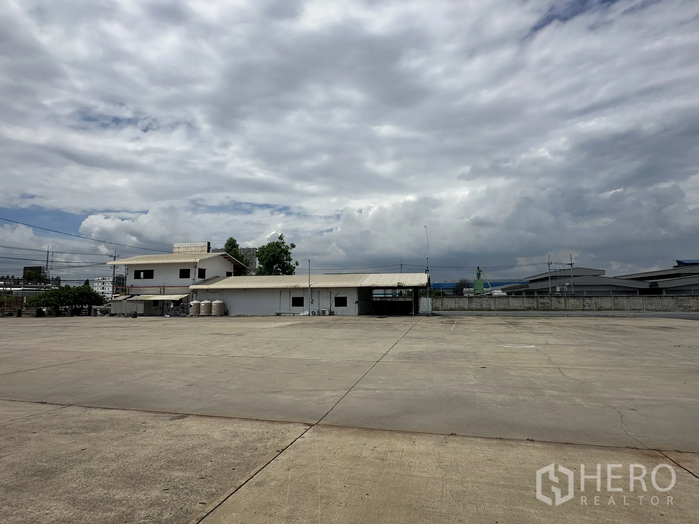 Land for rent in Wang Noi, Phra Nakhon Si Ayutthaya - Open concrete yard with boundary walls and low buildings around the site.