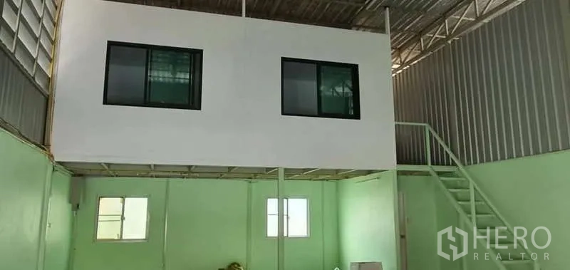 คลังสินค้า ให้เช่าในKhlong Toei, Bangkok - พื้นที่โกดังเพดานสูงพร้อมสำนักงานชั้นลอย ผนังสีเขียวอ่อน และโครงหลังคาเหล็ก.