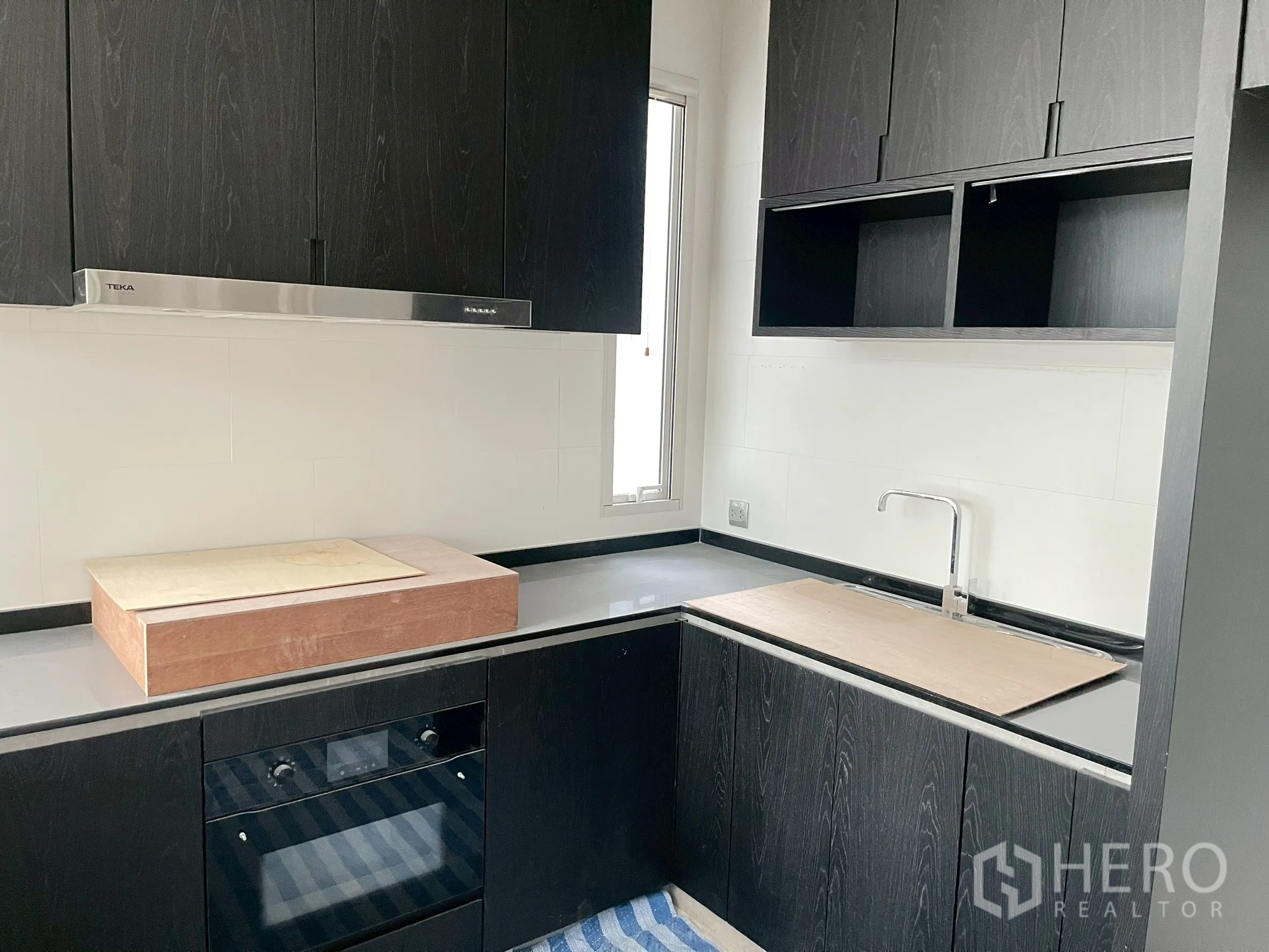 Detached House for sale in Bang Phli, Samut Prakan - Compact kitchen with black cabinets, oven and L-shaped countertop.