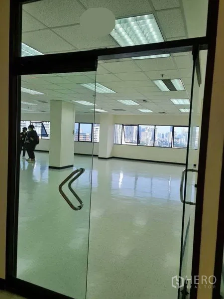 Office Space for rent in Watthana, Bangkok - Glass double-door entrance opening to a bright office with large windows and city skyline views.