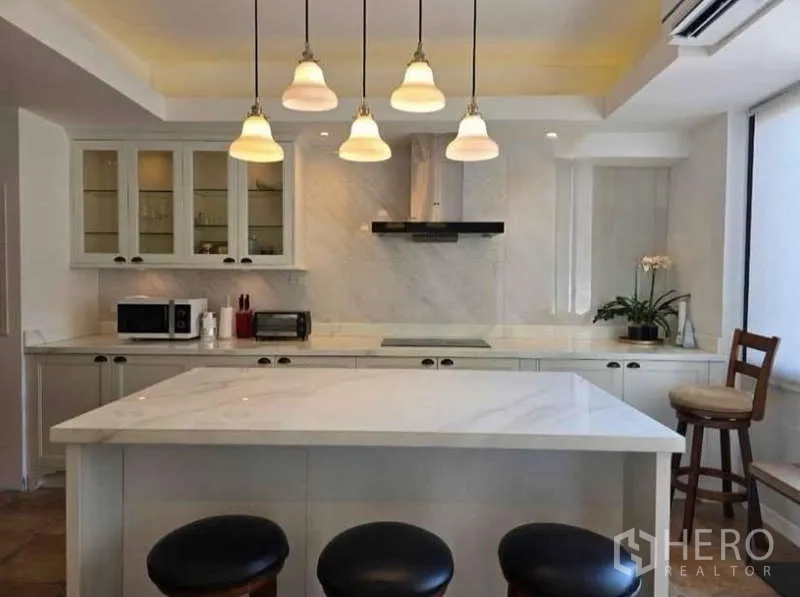 Townhouse for rent - White island kitchen with marble countertops, pendant lights, and built-in appliances.