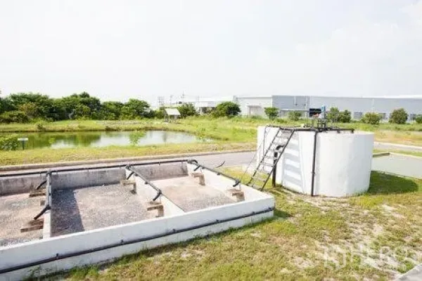 Factory for rent in Chachoengsao - Settling pond and concrete treatment tanks beside greenery within the industrial property.