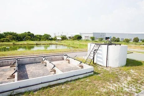 Factory for rent in Chachoengsao - Settling pond and concrete treatment tanks beside greenery within the industrial property.