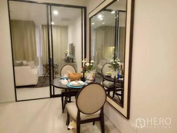 Condominium for rent or sale in Pathum Wan, Bangkok - Compact dining area set for two beside a large wall mirror and sliding glass doors to the living area.