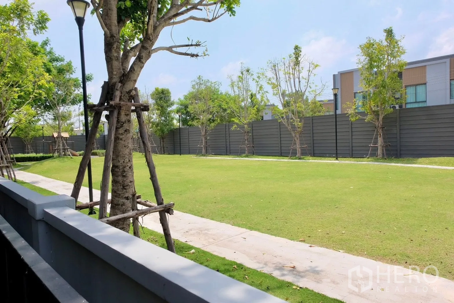 Semi-detached House for sale in Prawet, Bangkok - Landscaped communal lawn with walking path, trees and fence.