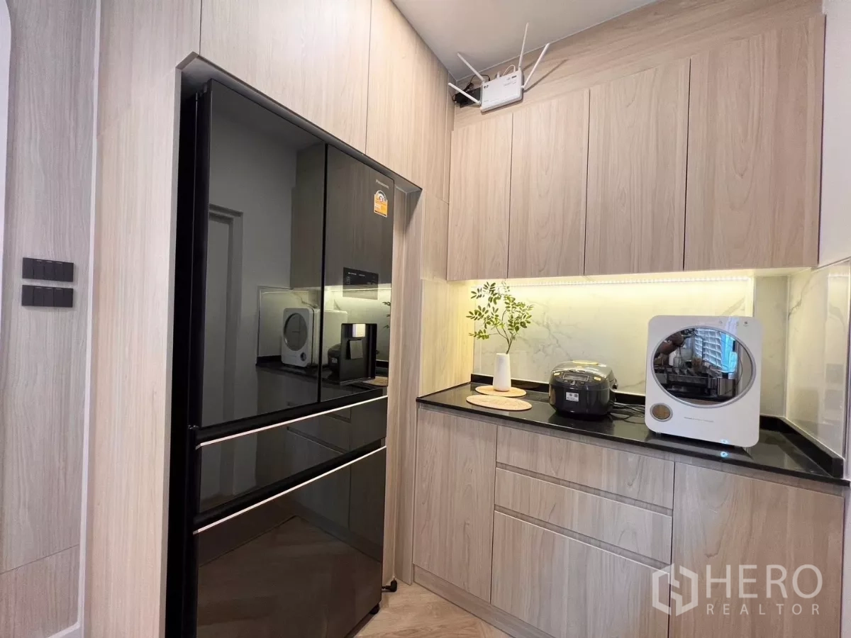 Detached House for rent in Bang Phli, Samut Prakan - Pantry wall with large black refrigerator, upper cabinets and task lighting.