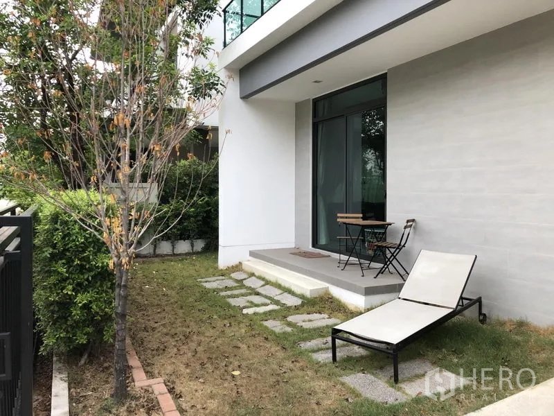 独立式住宅 出租在Saphan Sung, Bangkok - 私家庭院设露台与户外桌椅，侧院摆放日光躺椅。