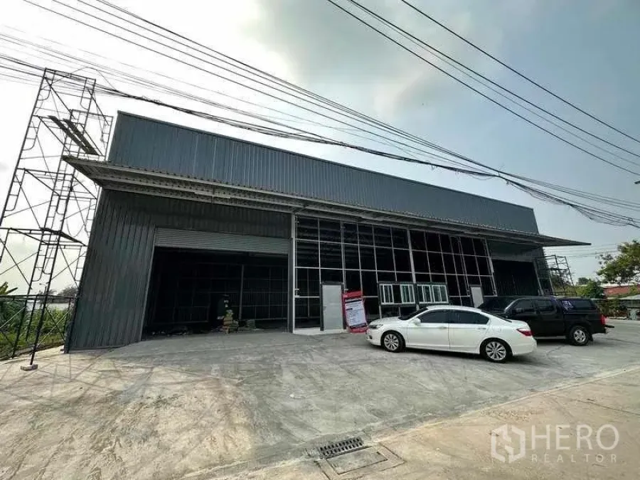 Warehouse for rent in Pak Kret, Nonthaburi - New steel-clad warehouse exterior with large roller shutter, glass-front office and wide parking apron in Pak Kret.