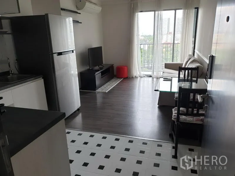Condominium for rent in Watthana, Bangkok - Bright living area opening to a balcony with city view, dining set, and kitchen.