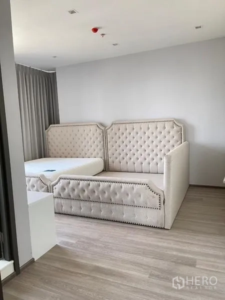 Condominium for rent in Bang Kho Laem, Bangkok - Alternate angle of bedroom with tufted bed and light wood flooring.