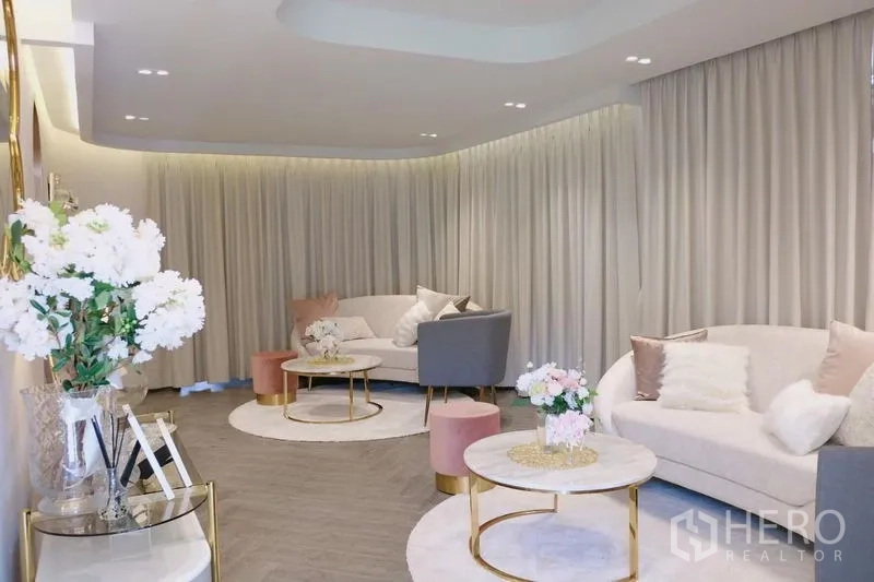 Detached House for rent in Huai Khwang, Bangkok - Soft-toned reception lounge with curved sofas, round marble tables and flowers.