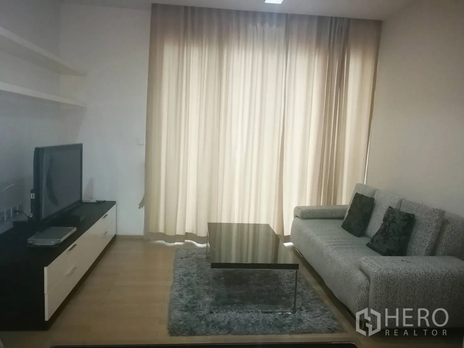 คอนโด ให้เช่าในKhlong Toei, Bangkok - ห้องนั่งเล่นสไตล์โมเดิร์นมีโซฟา ชั้นวางทีวี โต๊ะกลาง และผ้าม่านสูงจรดเพดาน