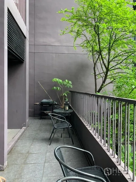 Condominium for sale in Watthana, Bangkok - Long private balcony with chairs and railing overlooking green trees.
