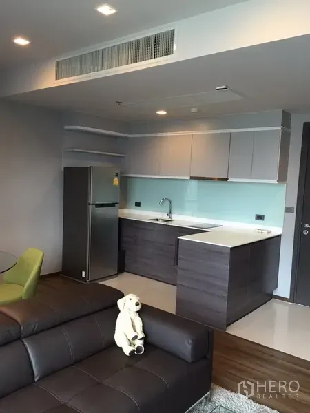 Condominium for rent in Watthana, Bangkok - Modern open-plan kitchen with glossy cabinets, glass backsplash, and full-size fridge in a Bangkok condo.