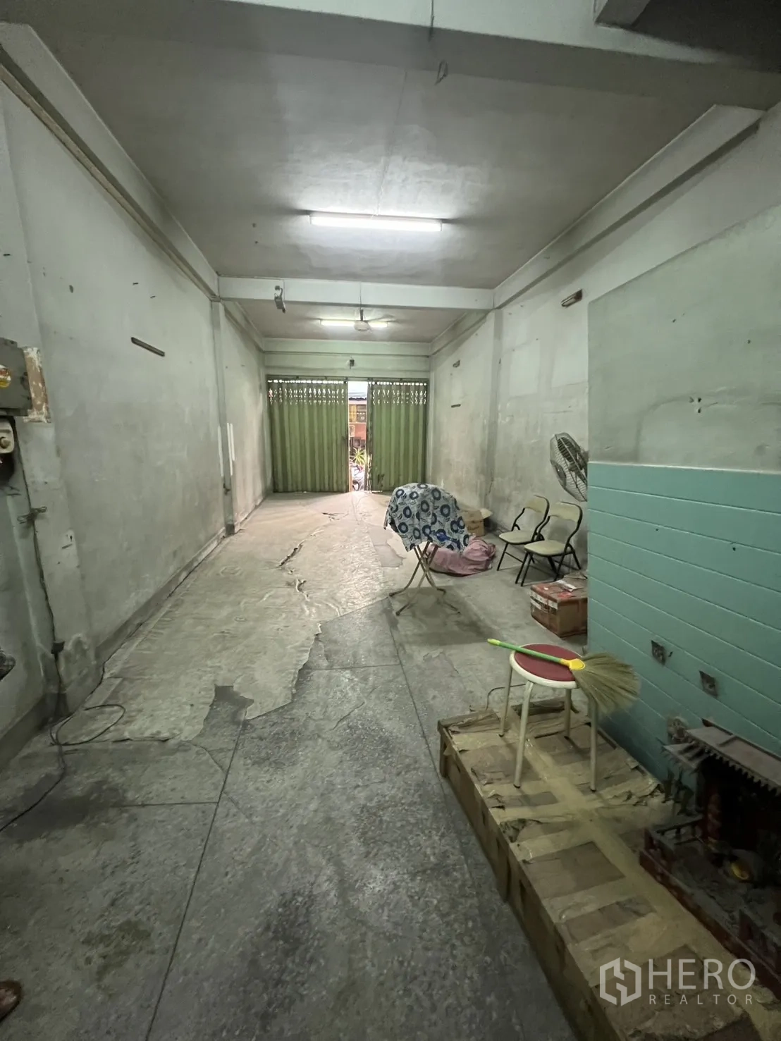 อาคารพาณิชย์ ให้เช่าในKhlong Toei, Bangkok - พื้นที่ชั้นล่างยาวปูคอนกรีต ผนังเปล่าและประตูเหล็กสีเขียวด้านหน้า