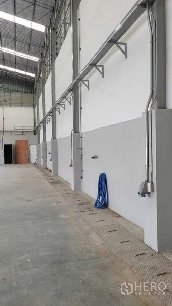 Warehouse for rent in Saphan Sung, Bangkok - Warehouse side wall featuring electrical conduits, power outlets, and a hose.