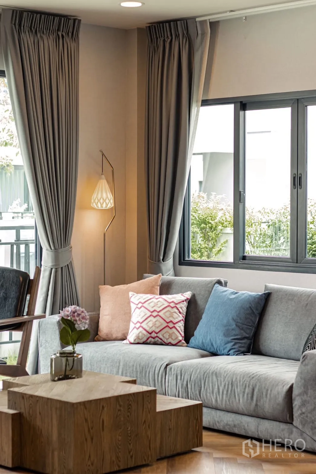 Detached House for rent in Bang Phli, Samut Prakan - Bright living room with gray sofa, floor lamp, wood coffee table, and large curtained windows.