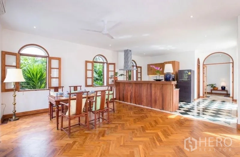 บ้าน ให้เช่าในPhra Khanong, Bangkok - ครัวเปิดพร้อมเคาน์เตอร์บาร์ยาว โต๊ะอาหาร และหน้าต่างโค้งหลายบานมองเห็นสวน